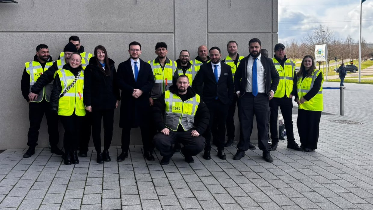 Gruppenfoto des GERD Teams in Warnwesten und Anzügen vor einer Gebäudewand